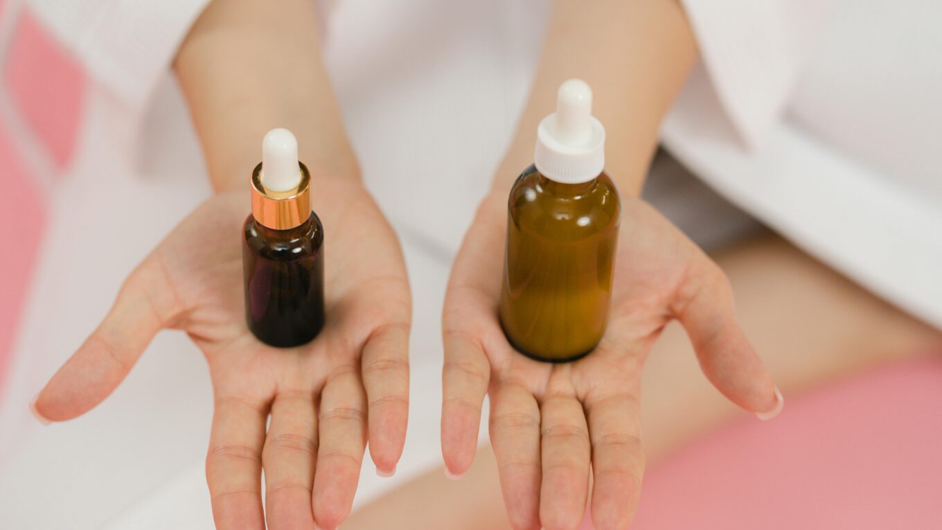 mãos femininas mostrando 2 produtos de skincare. niacinamida e vitamina c - um produto em cada mão.